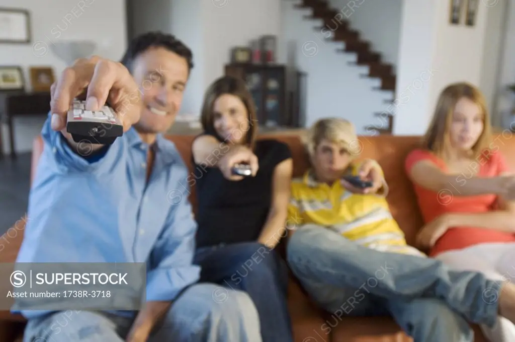 Parents and two teens holding eachothers a remote control, indoors