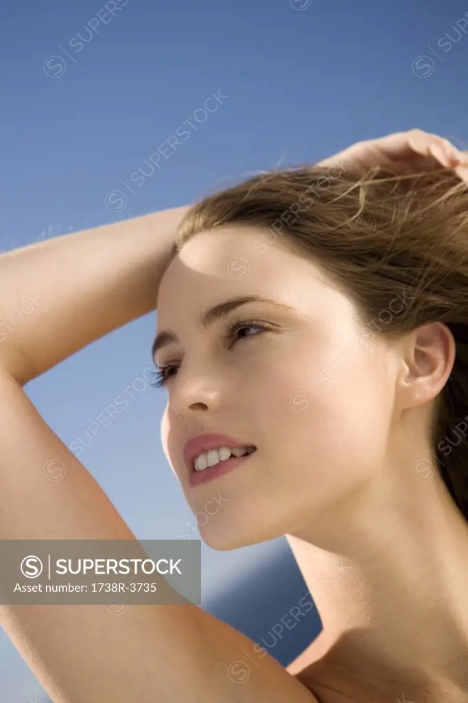 Portrait of a young woman looking away, hand in her hair, outdoors
