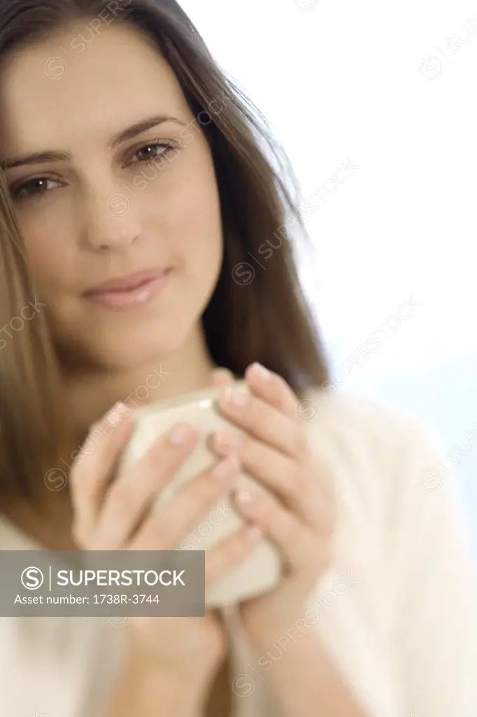 Portrait of a young woman holding a cup, indoors