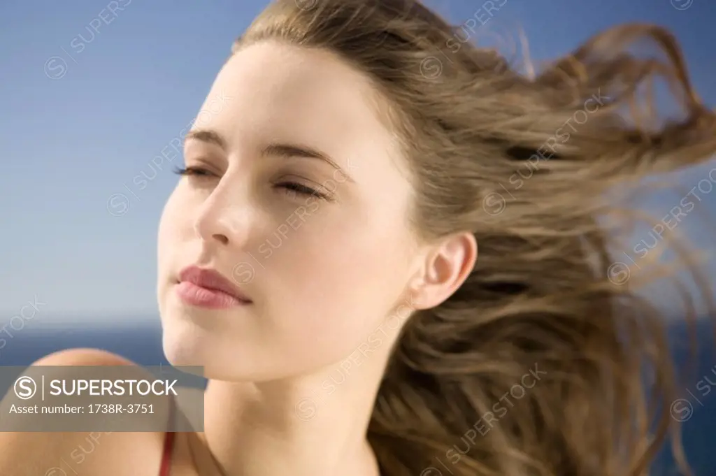 Portrait of a young woman looking away, wind in her hair, outdoors