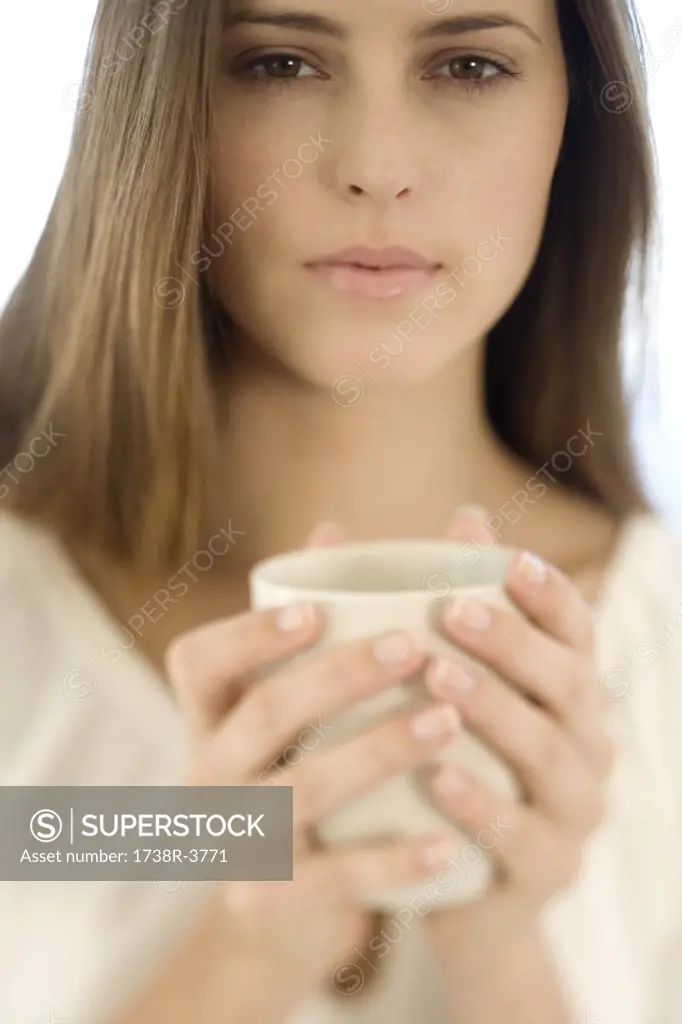 Portrait of a young woman holding a cup, indoors
