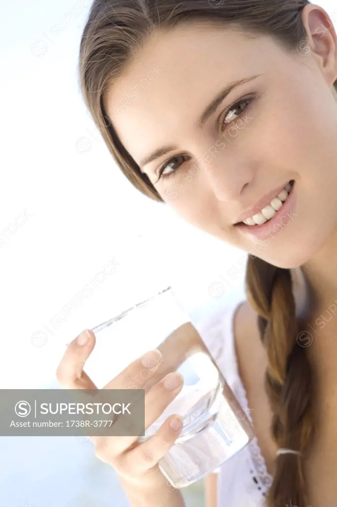 Portrait of a young woman holding a water glass, outdoors