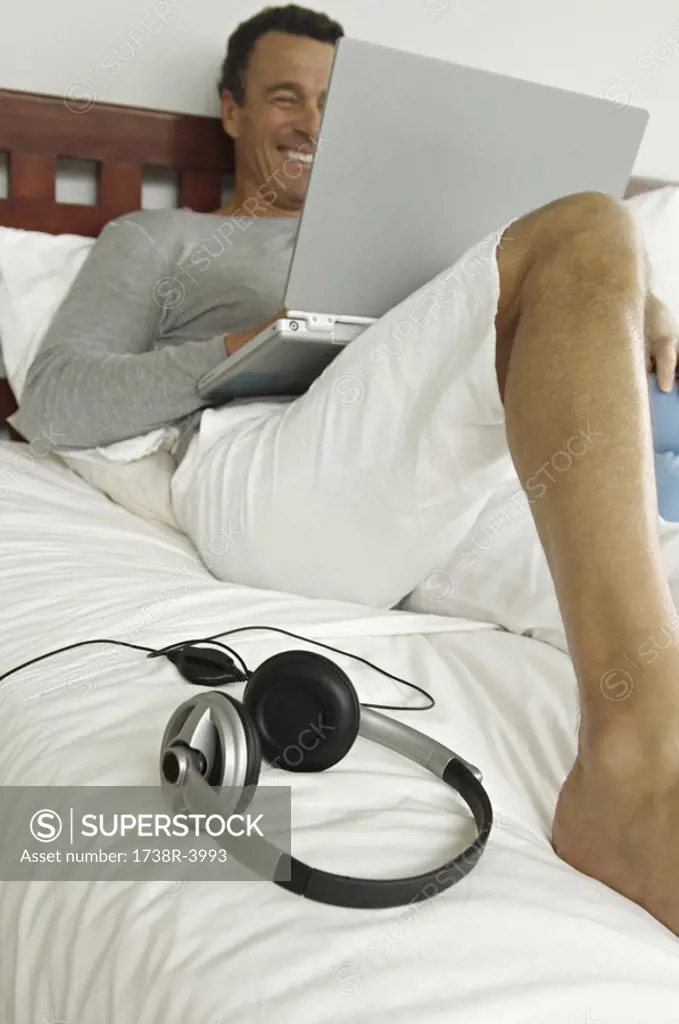 Man lying on bed, using laptop