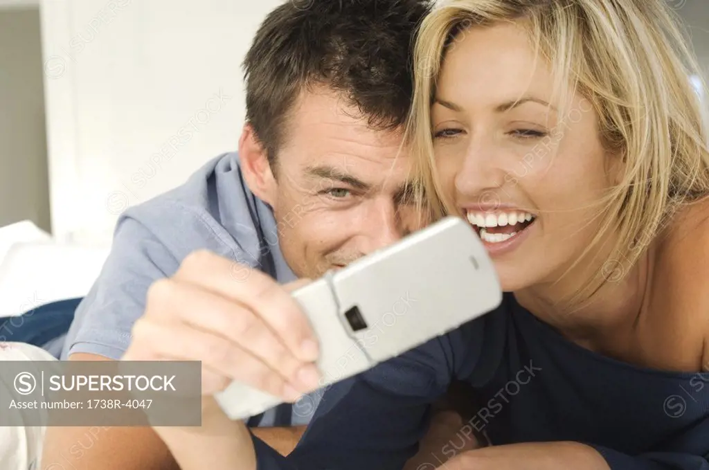 Young couple in bed, using mobile phone