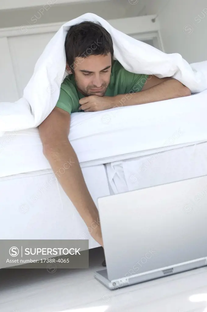 Young man using laptop in bed
