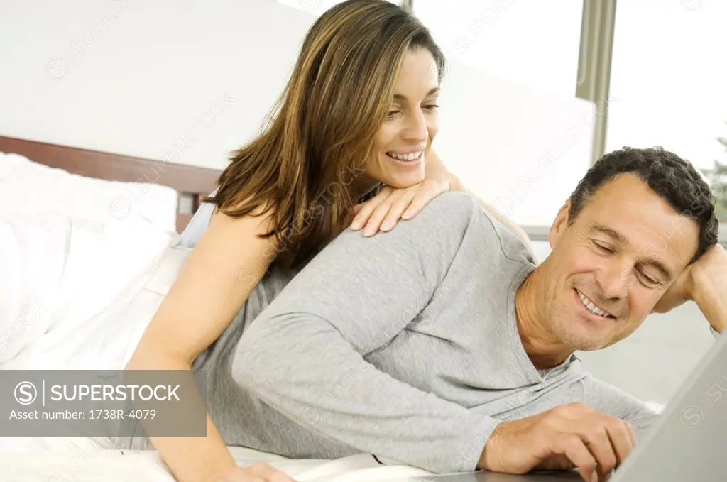 Couple in bed, using laptop