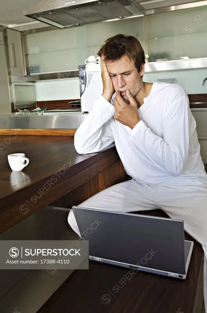 Young man using laptop in kitchen