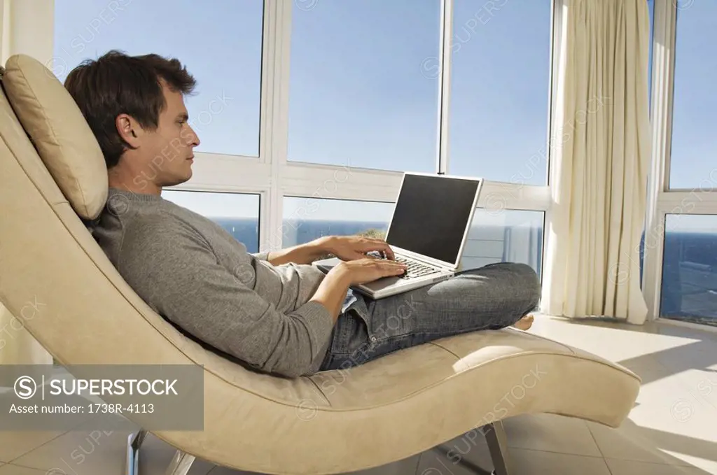 Young man using laptop in armchair