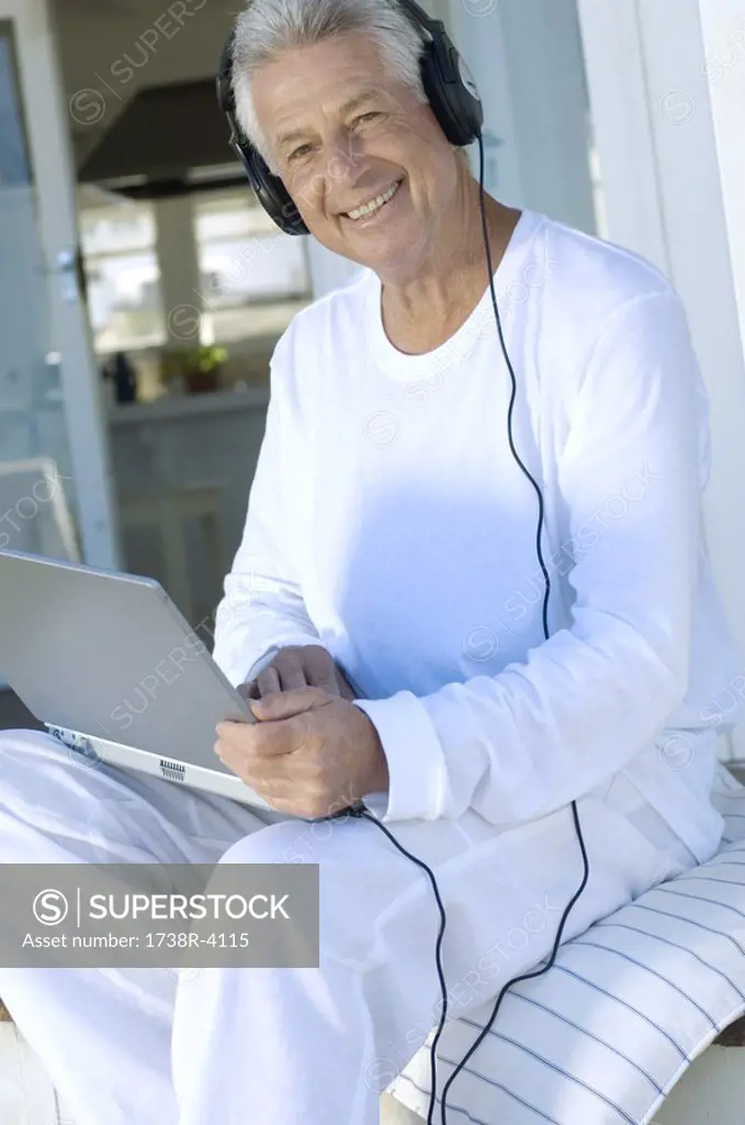 Smiling man with headphones using laptop