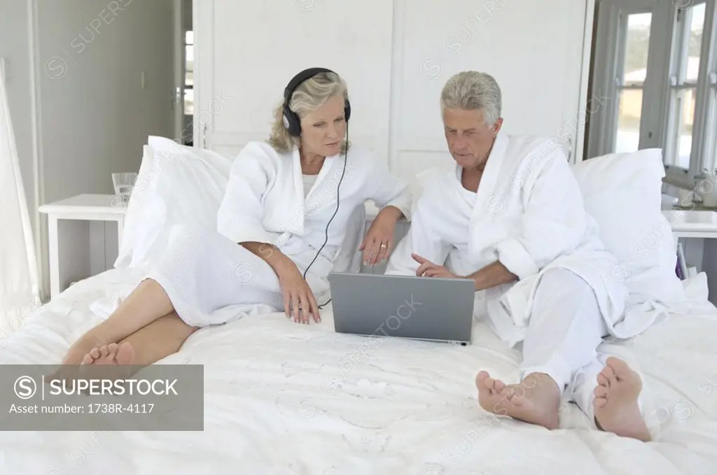 Couple using laptop in bed