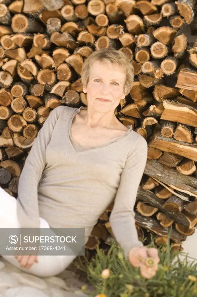 Senior woman sitting by woodpile