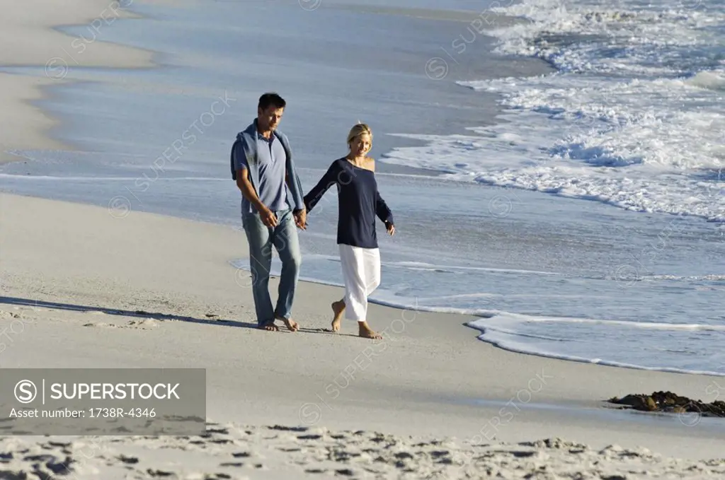 Couple holding hands, walking on the beach