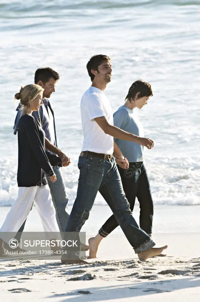 2 couples holding hands, walking on the beach