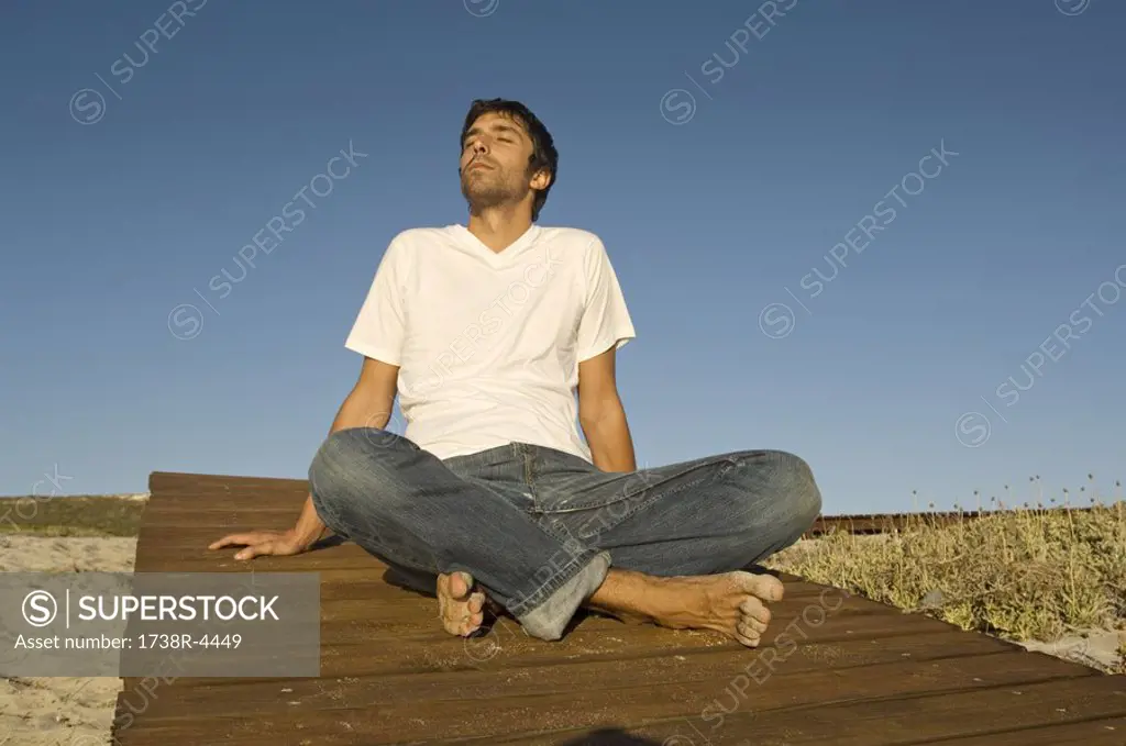 Young man sitting cross-legged, outdoors