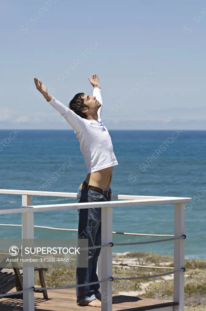 Young man stretching on terrace, sea in background