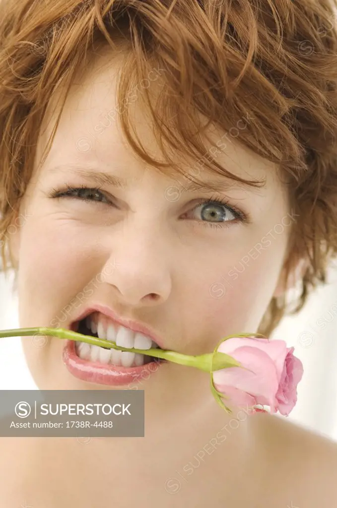 Portrait of young woman with rose between teeth