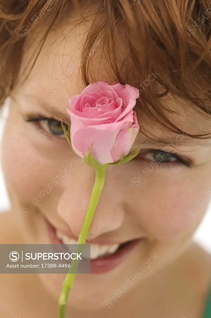 Portrait of young woman with rose in front of face