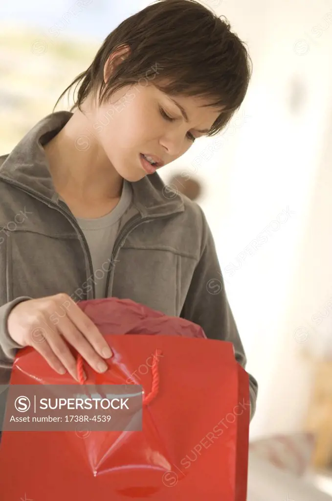 Young woman opening bag, looking disappointed