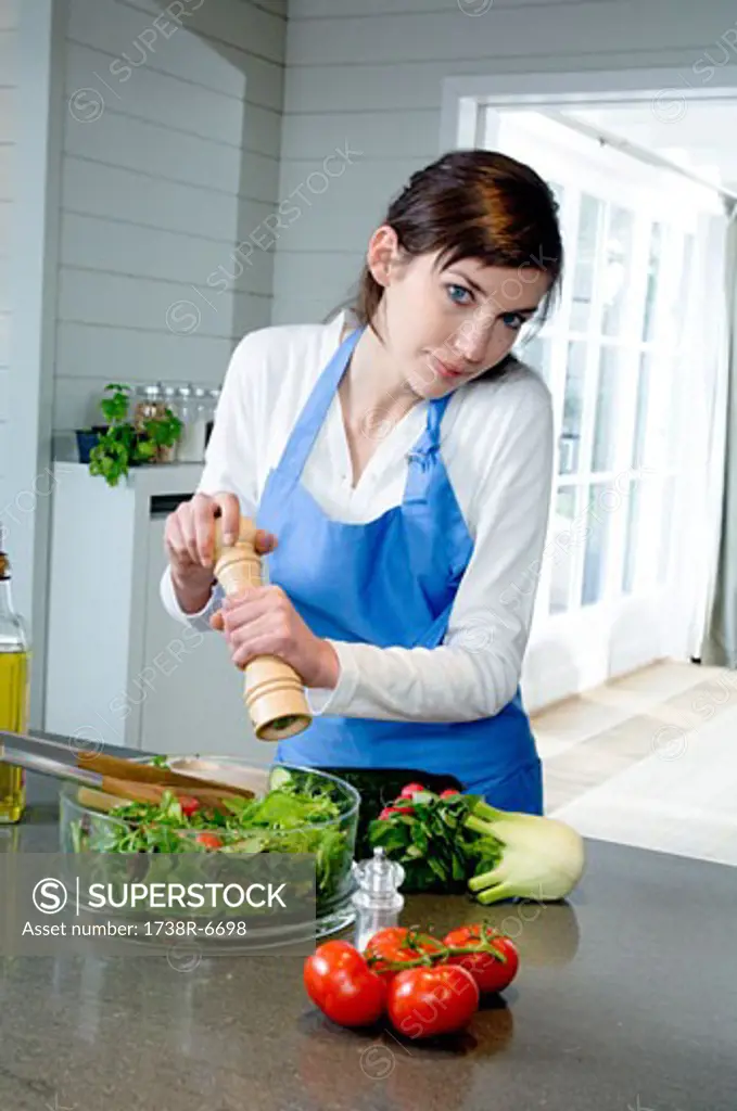Young woman seasoning a salad