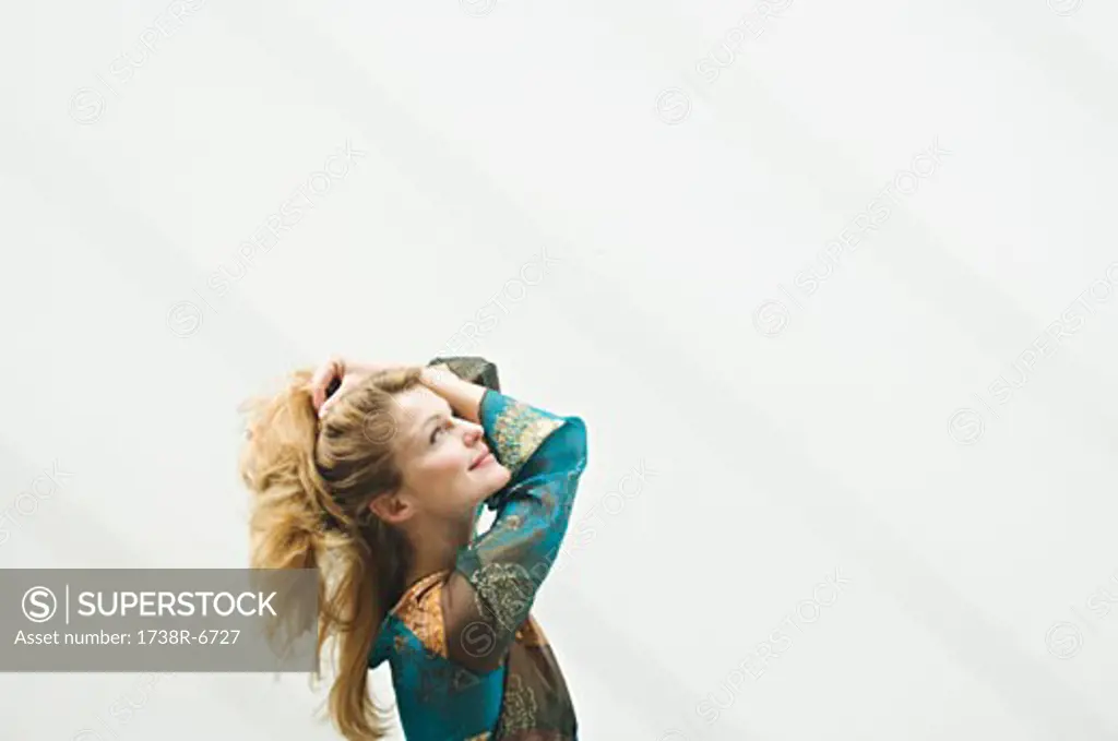Young woman in profile looking up, hands in hair