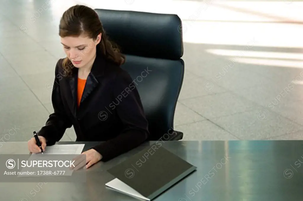 Businesswoman sitting at a desk and signing documents