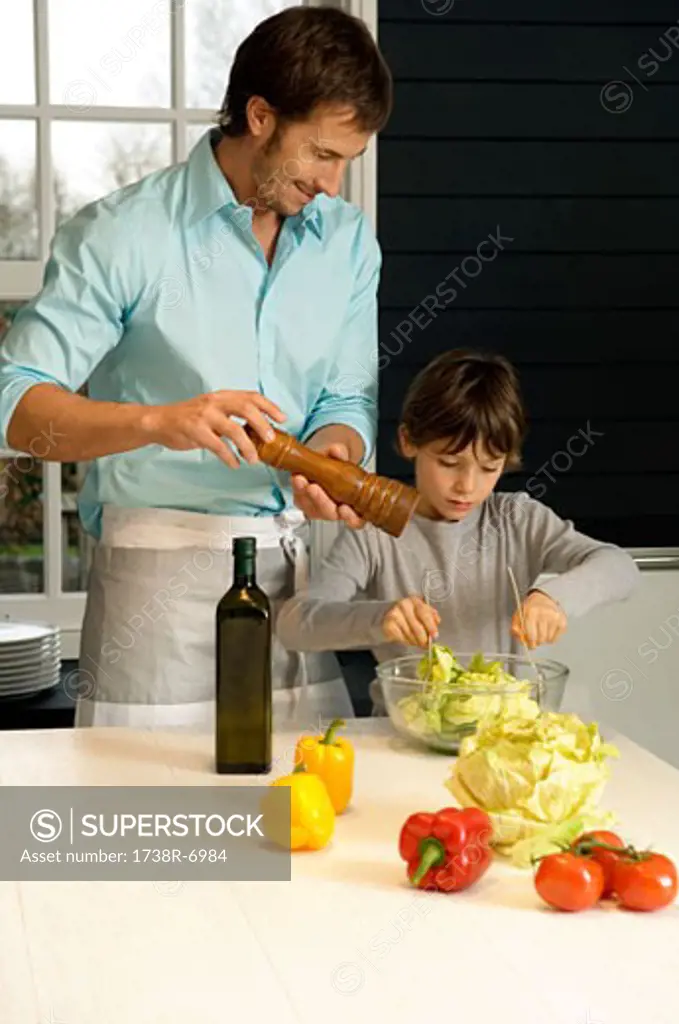 Mid adult man preparing food with his son in the kitchen