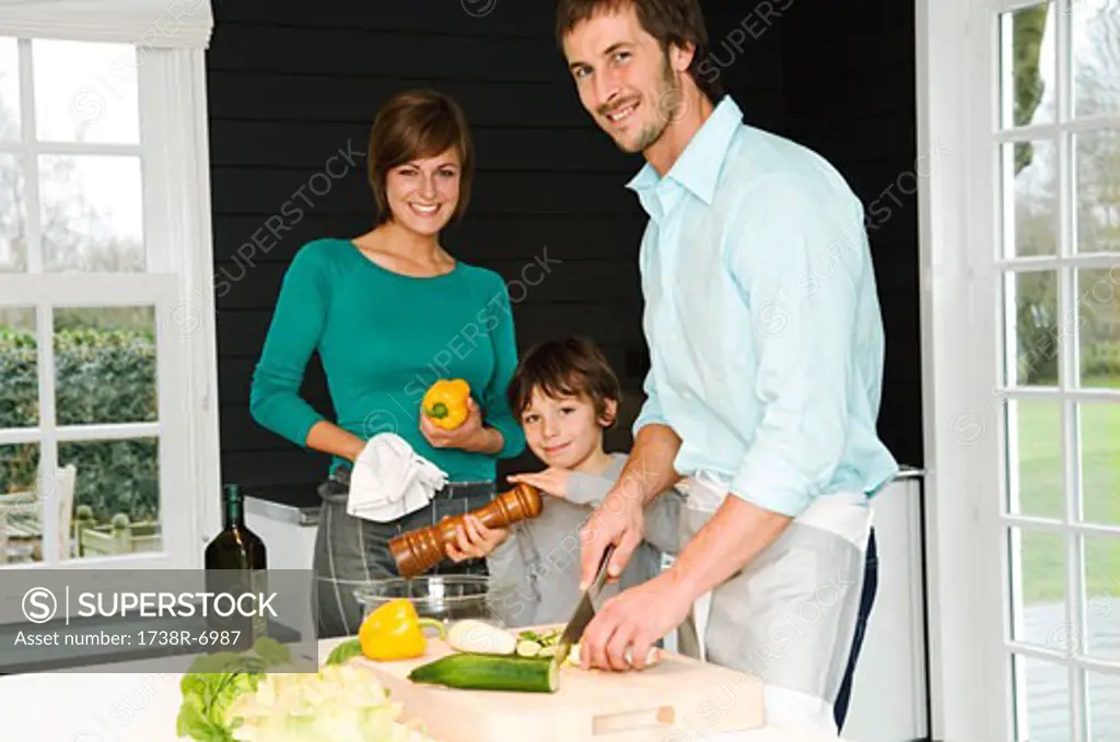 Mid adult man and a young woman preparing food with their son