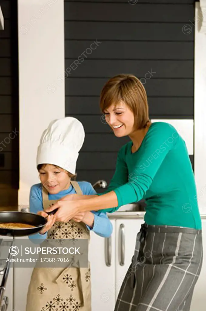 Young woman preparing a pancake with her son