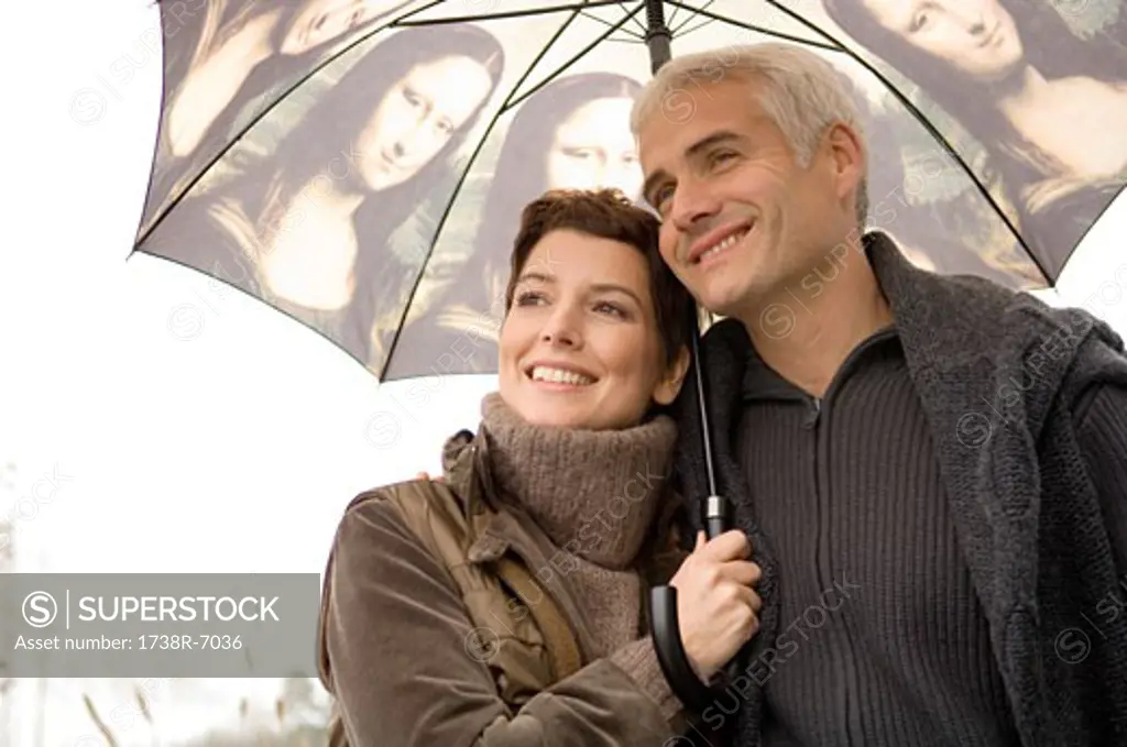 Close-up of a mid adult woman and a mature man under an umbrella