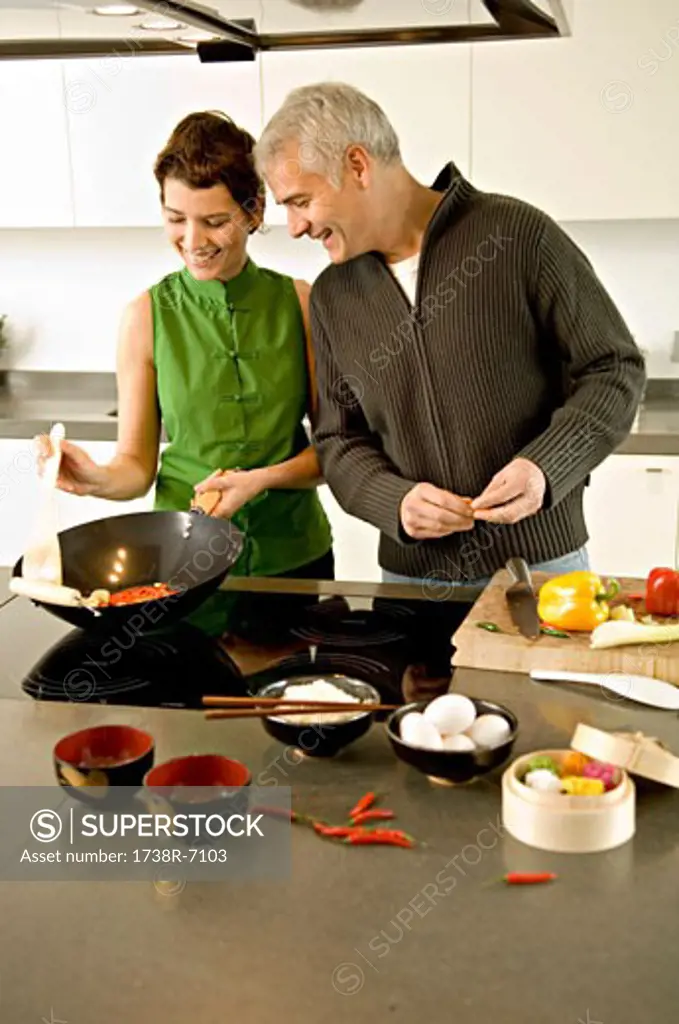 Mature man and a mid adult woman preparing food in the kitchen