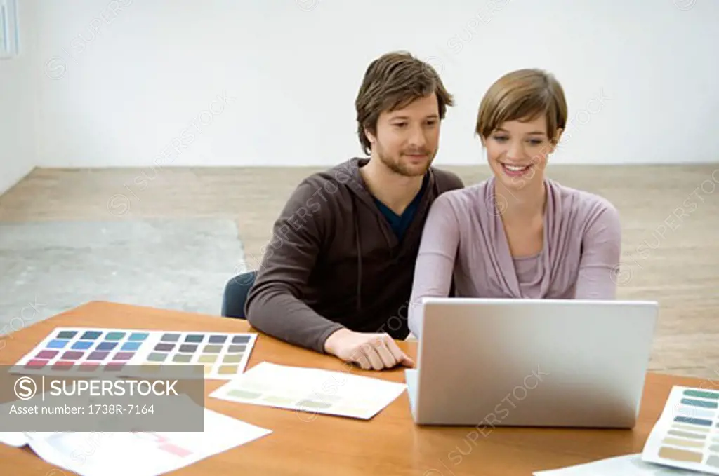 Mid adult man and a young woman using a laptop and smiling