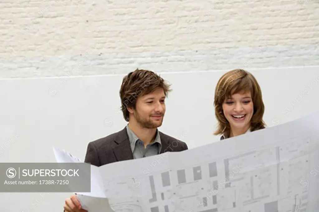 Mid adult man and a young woman looking at a blueprint