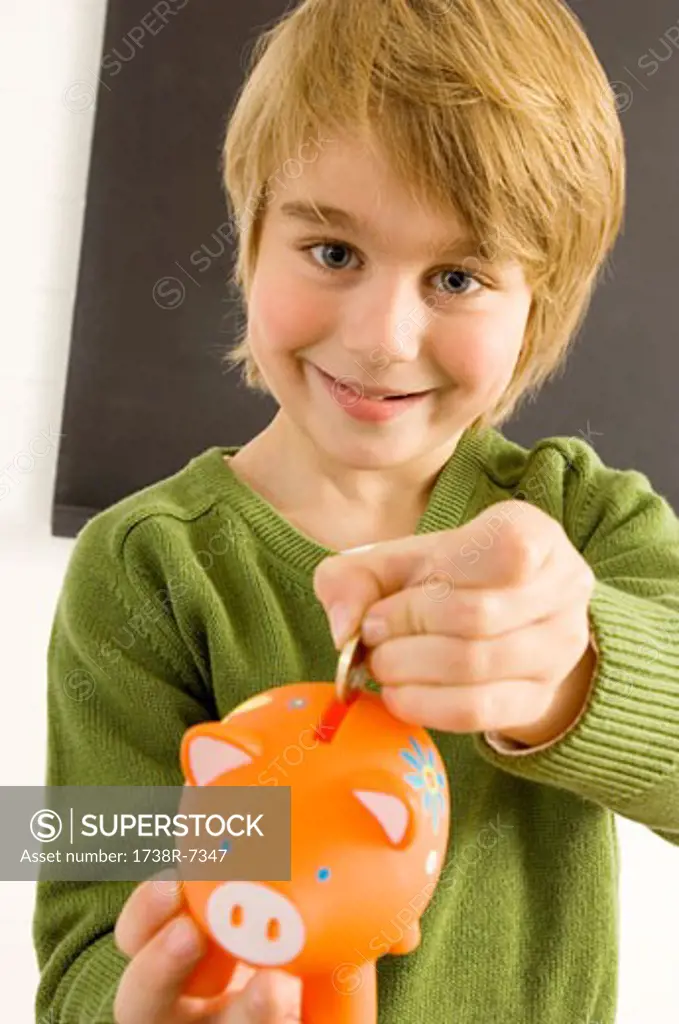 Boy putting a coin into a piggy bank