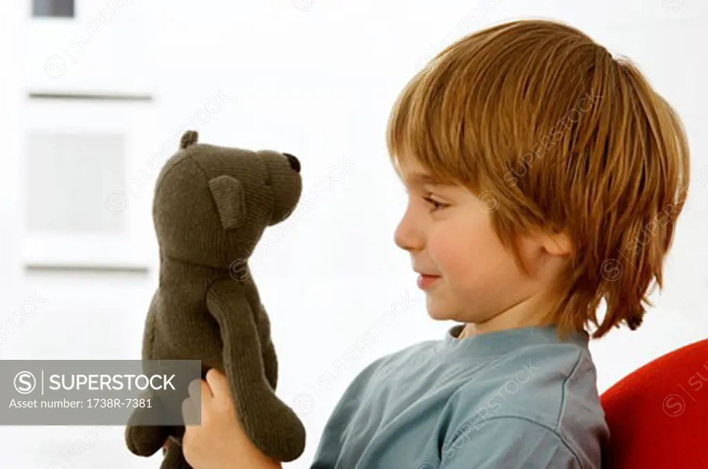 Side profile of a boy holding a teddy bear