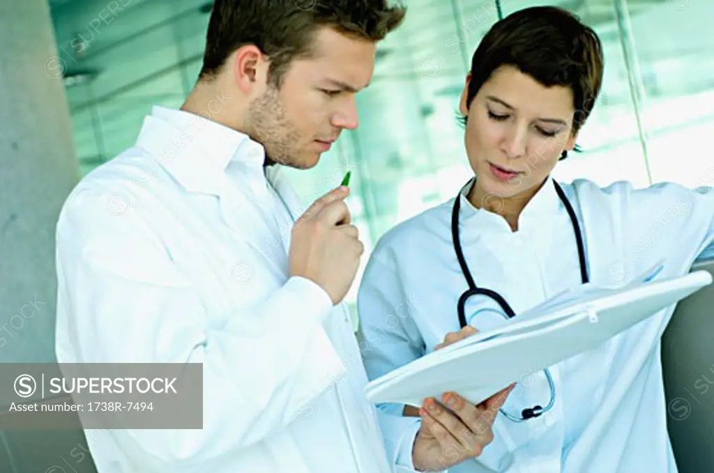 Close-up of two doctors discussing a medical record