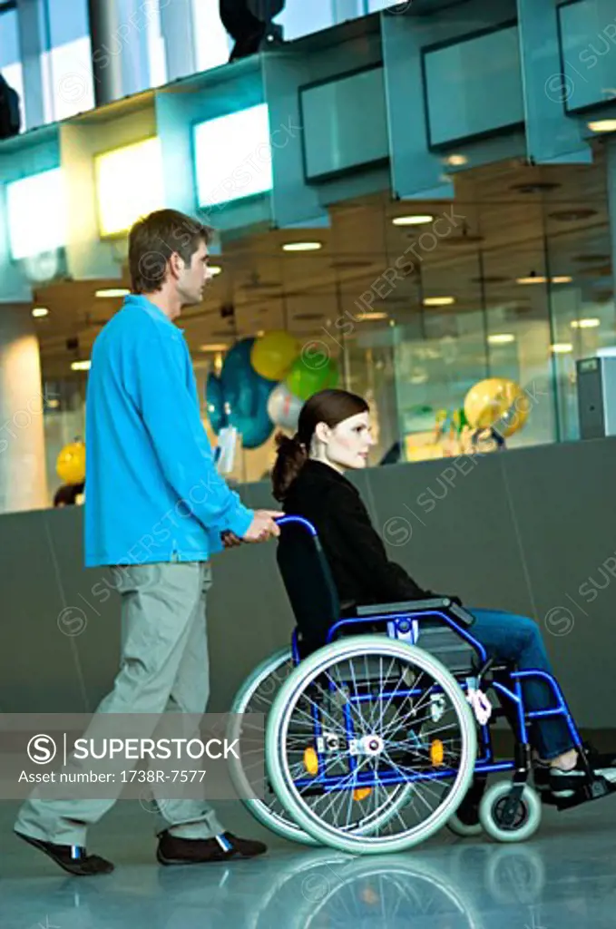 Side profile of a mid adult man pushing a young woman sitting in a wheelchair