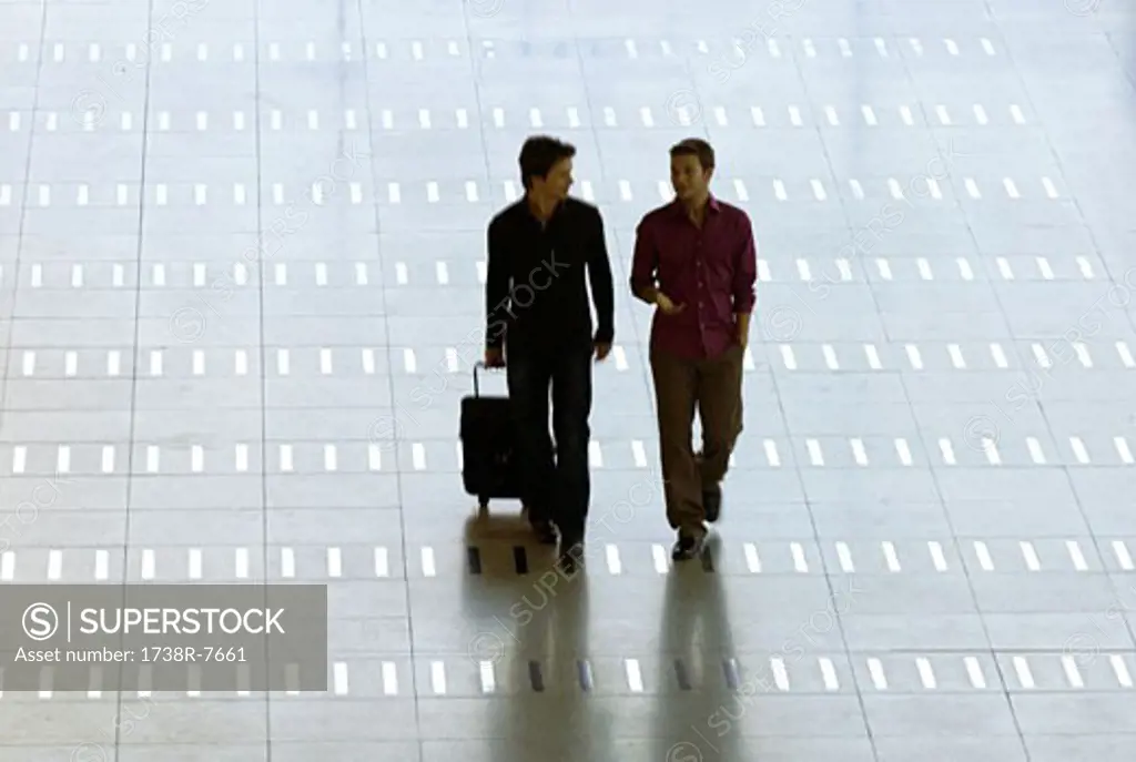 Mid adult man walking with a young man at an airport