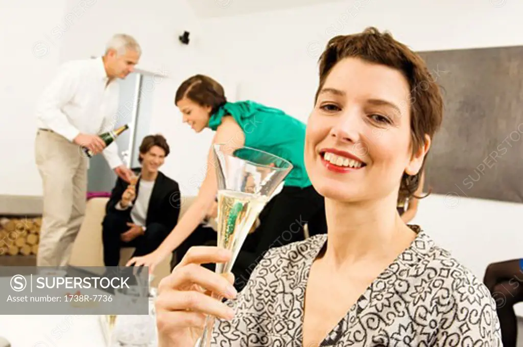 Mid adult woman holding a wine glass with three people in the background
