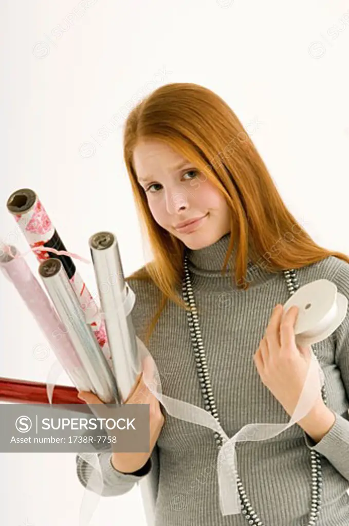 Portrait of a young woman holding rolls of wrapping papers