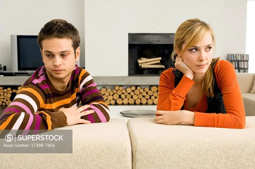 Young couple leaning on a couch and looking serious