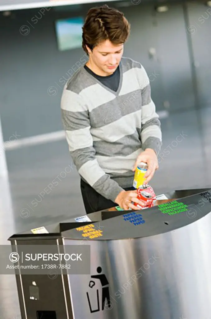 Mid adult man putting empty cans into a garbage bin