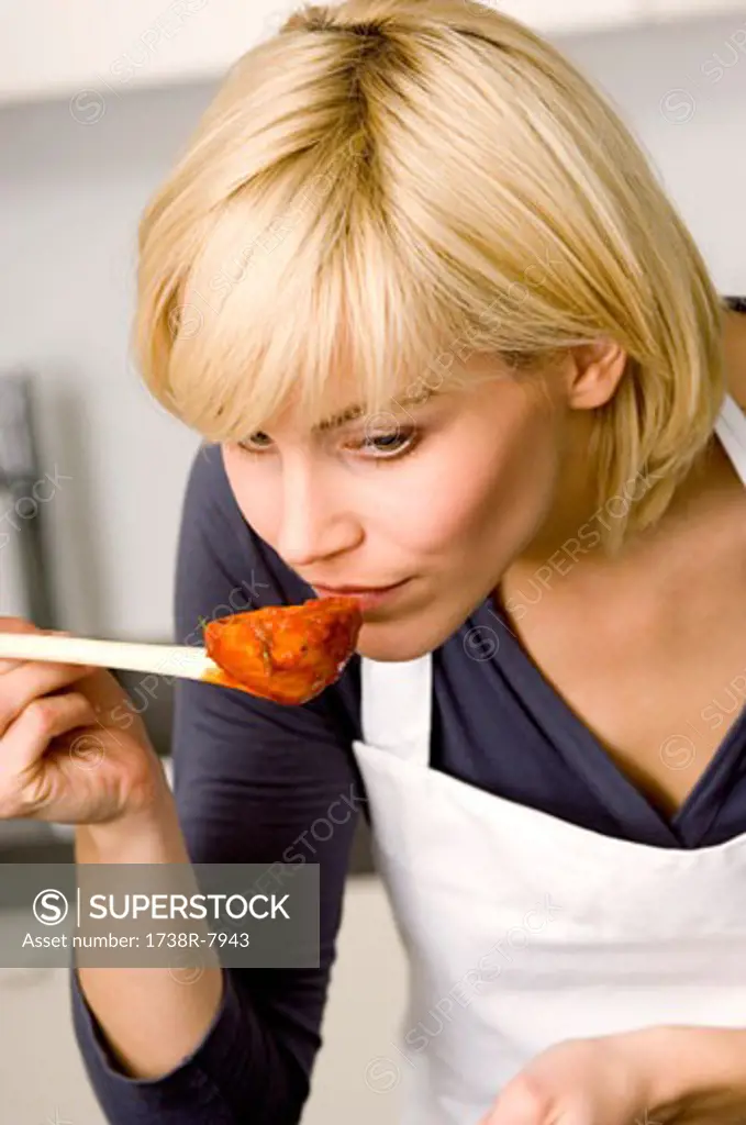 Close-up of a young woman smelling tomato sauce