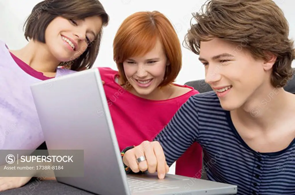Close-up of two young women and a teenage boy looking at a laptop