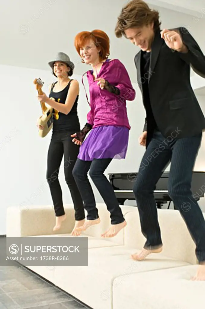 Two young women and a teenage boy dancing on a couch