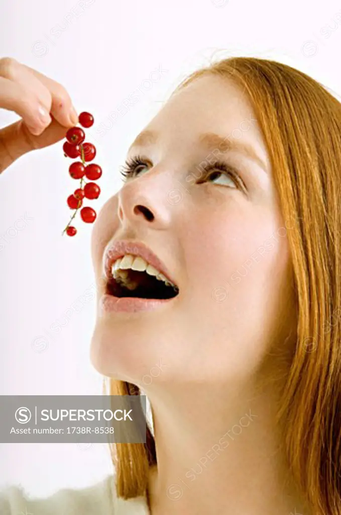 Close-up of a young woman eating red currants