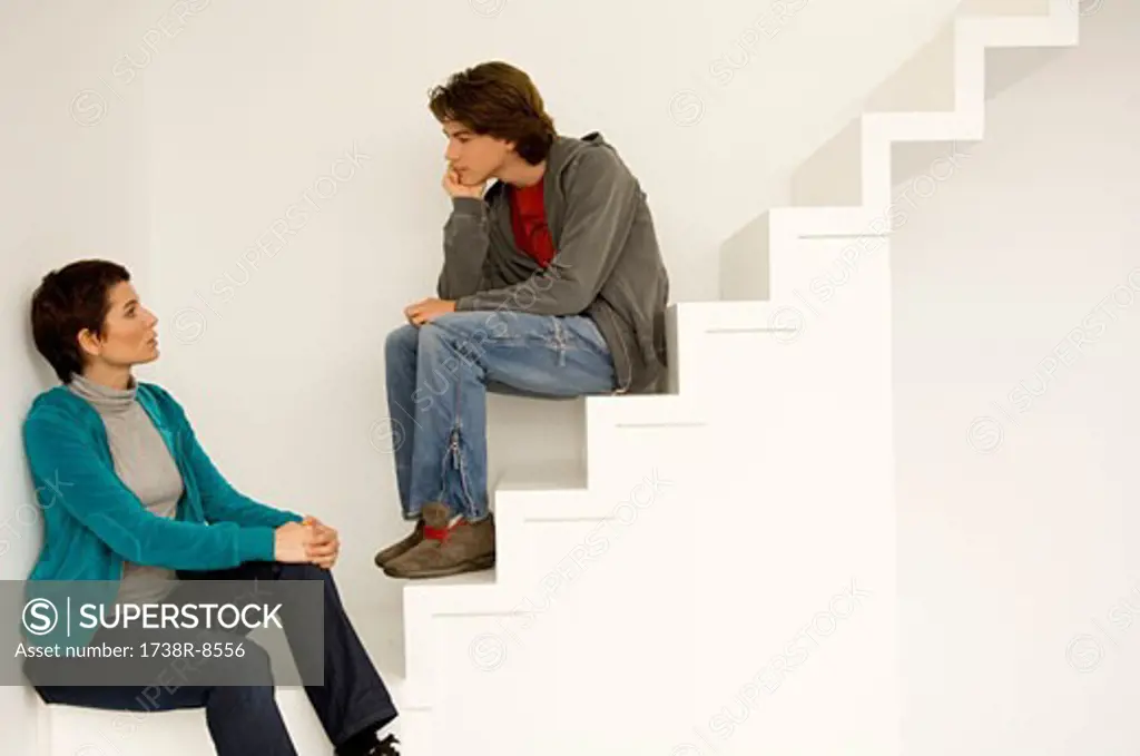 Mid adult woman and her son sitting on a staircase