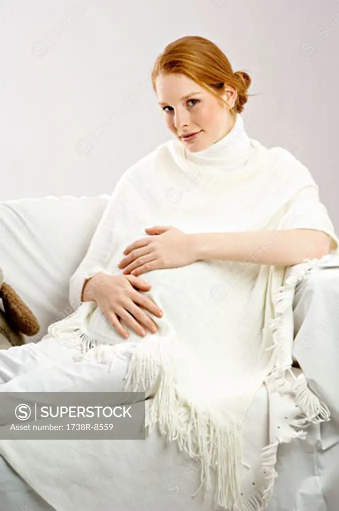 Portrait of a pregnant young woman sitting on a couch and smiling