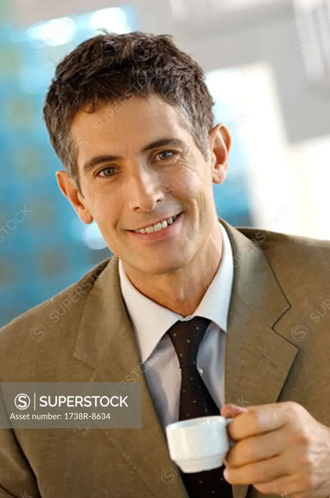 Mid adult businessman holding cup of coffee, portrait