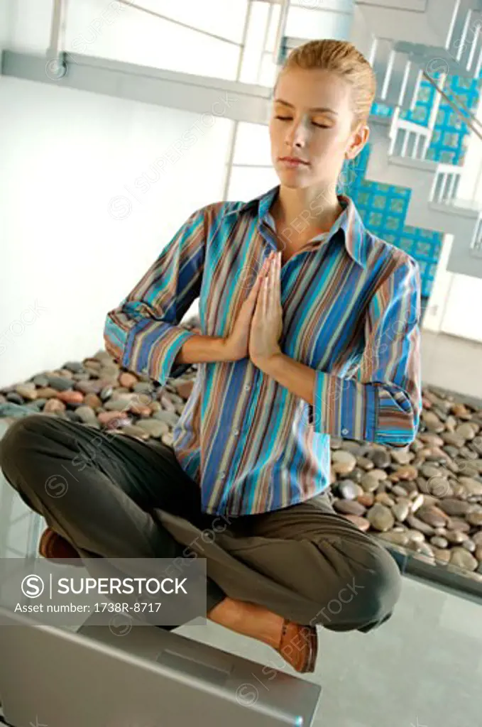 Young businesswoman meditating on glass table