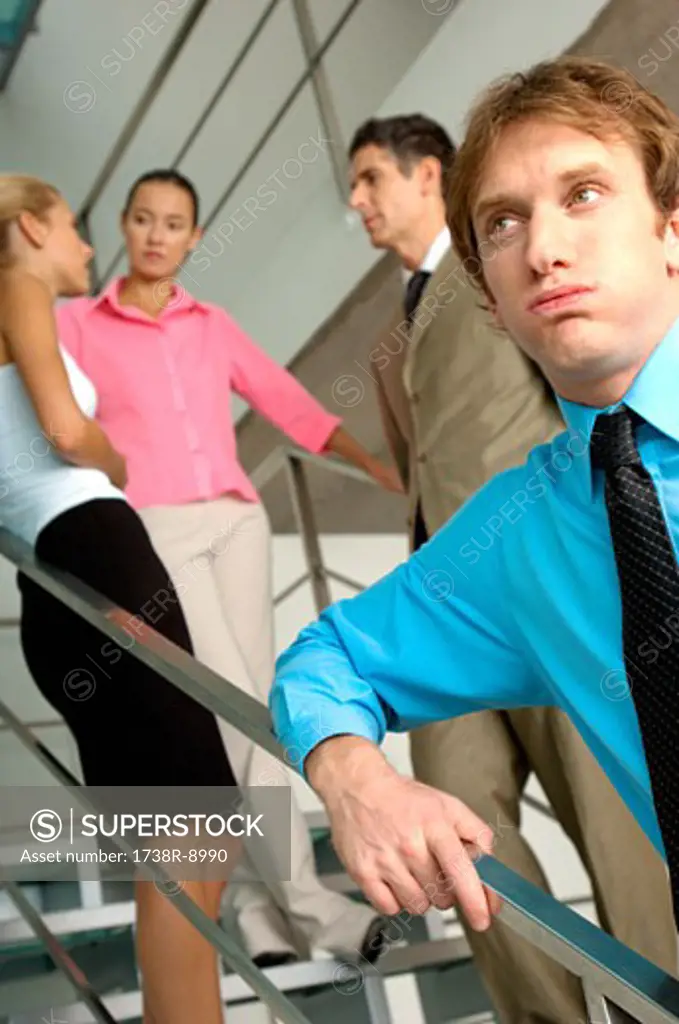 Businessman standing by staircase with colleagues in background
